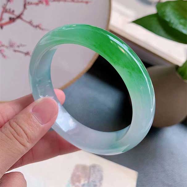 紫底辣色正圈翡翠手镯 尺寸：56/13.5/8.5mm 紫底味，辣绿色艳丽，整体糯化显底色，版型端庄典雅，上手华贵抢眼 ：六位数  喜询